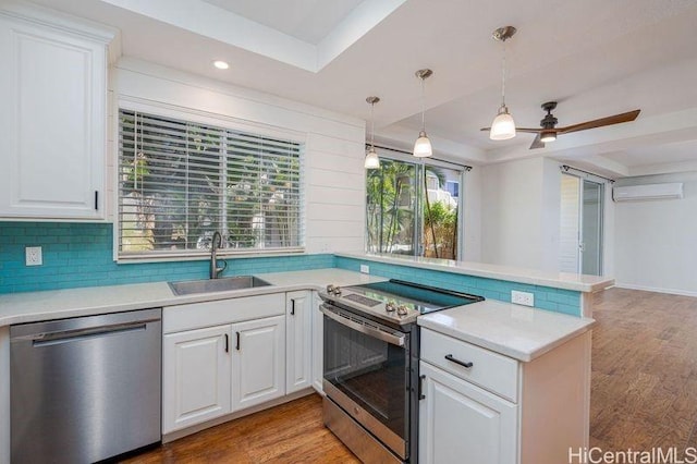 kitchen featuring stainless steel appliances, white cabinetry, a tray ceiling, and kitchen peninsula