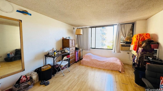 bedroom featuring radiator, light wood-style floors, cooling unit, and a textured ceiling