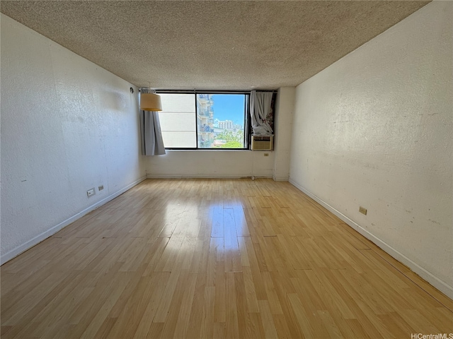444 Niu St Unit 815, Honolulu, HI 96815 - empty room featuring a textured wall, light wood-style flooring, baseboards, and a textured ceiling