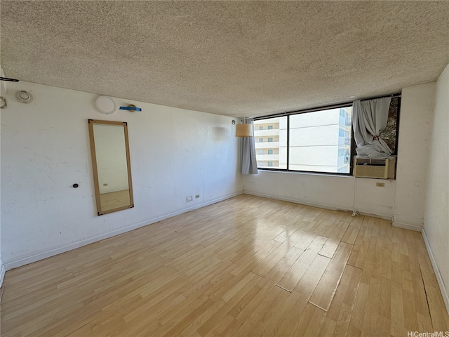 444 Niu St Unit 815, Honolulu, HI 96815 - empty room featuring light wood finished floors, cooling unit, baseboards, and a textured ceiling