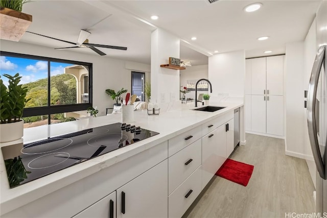 kitchen featuring sink, stainless steel appliances, light hardwood / wood-style floors, light stone countertops, and white cabinets