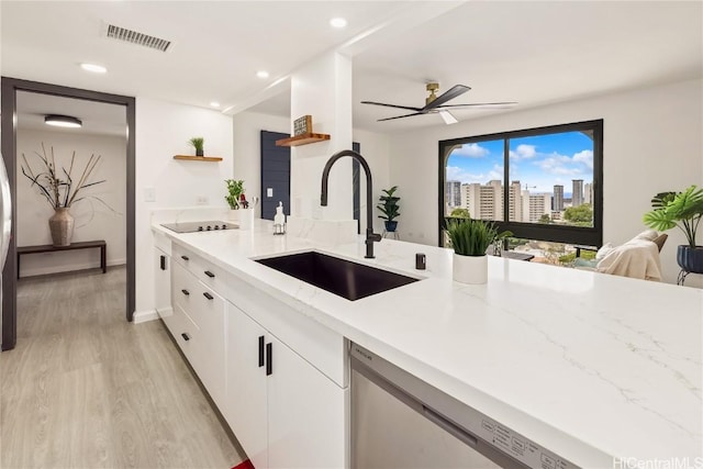 kitchen featuring dishwasher, sink, white cabinets, light stone counters, and light wood-type flooring