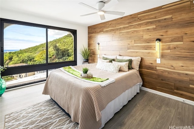 bedroom with ceiling fan, wooden walls, and dark hardwood / wood-style flooring