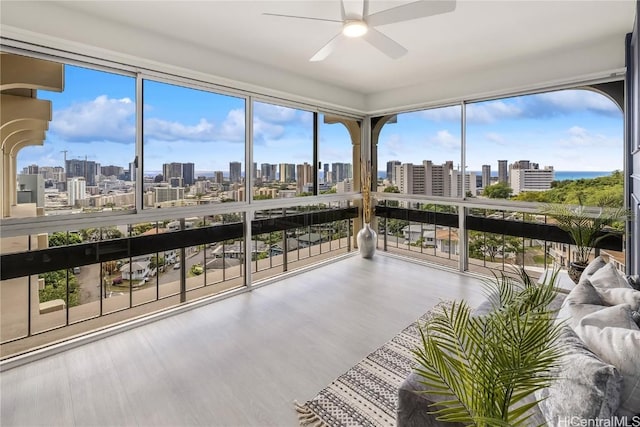 sunroom with plenty of natural light, a ceiling fan, and a city view