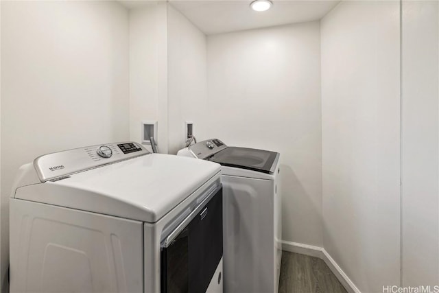 washroom with laundry area, baseboards, washing machine and clothes dryer, and wood finished floors