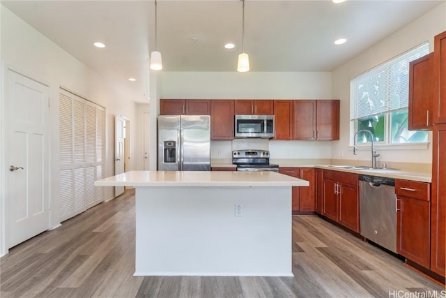 kitchen featuring a center island, stainless steel appliances, light countertops, light wood-style floors, and a sink