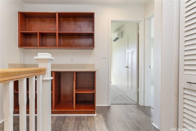 interior space with a wall unit AC, wood finished floors, and baseboards