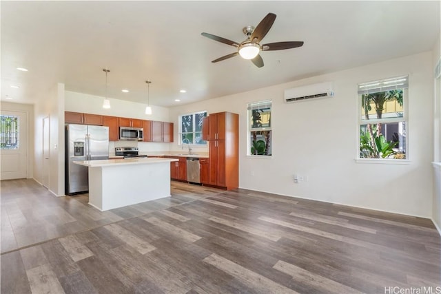 kitchen with a wall unit AC, brown cabinetry, stainless steel appliances, and wood finished floors