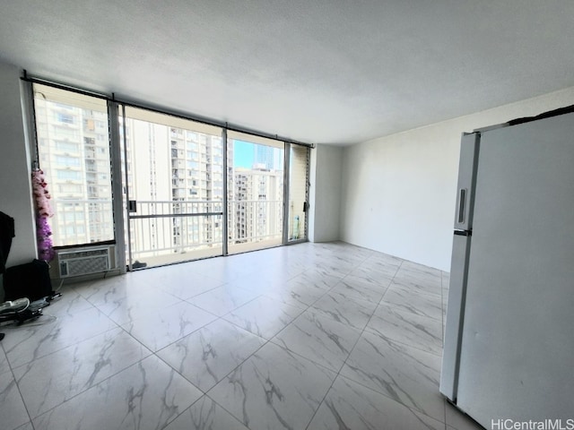 spare room featuring cooling unit, floor to ceiling windows, and a textured ceiling