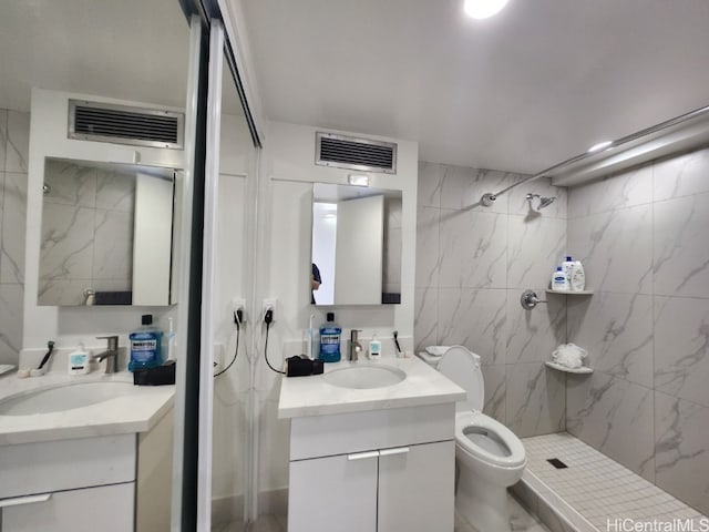 bathroom with vanity, a tile shower, and toilet