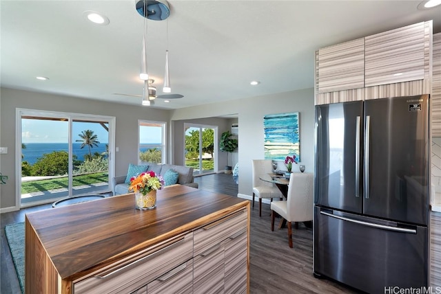 dining space featuring dark wood-type flooring, ceiling fan, and a water view