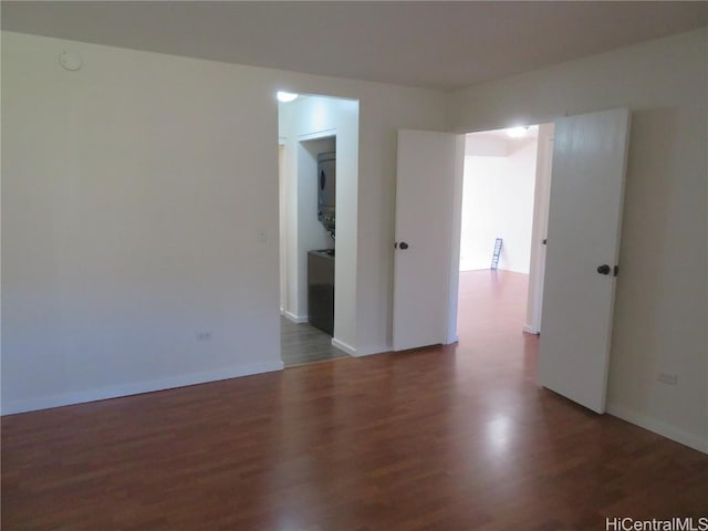 unfurnished room featuring stacked washer and clothes dryer and dark wood-type flooring