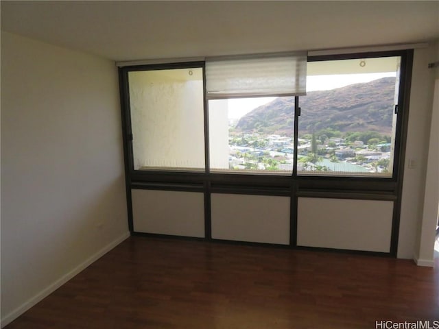 empty room featuring a mountain view and dark hardwood / wood-style floors