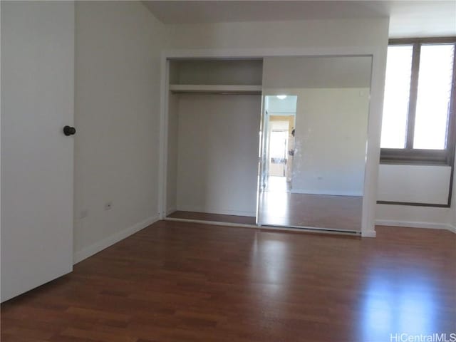 unfurnished bedroom featuring dark hardwood / wood-style flooring and a closet