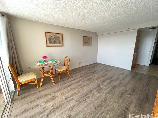 dining space with wood-type flooring and a textured ceiling