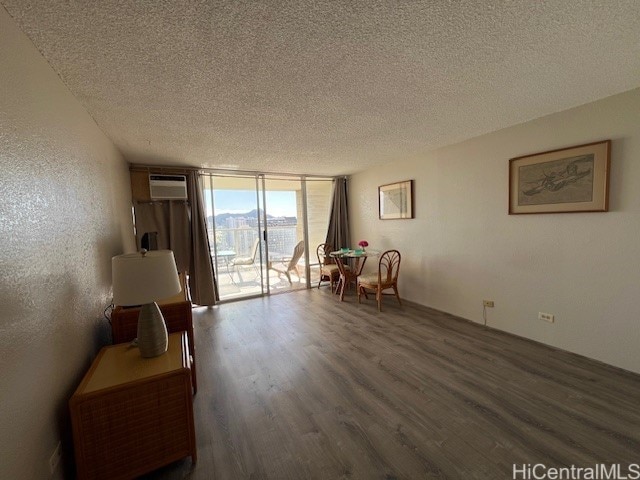 sitting room featuring an AC wall unit, a wall of windows, dark hardwood / wood-style floors, and a textured ceiling