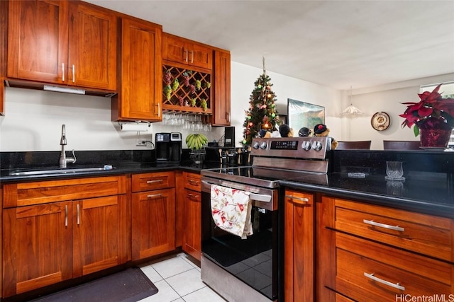 kitchen with light tile patterned flooring, sink, stainless steel electric range, and dark stone countertops