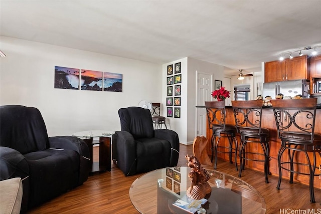 living room featuring wood-type flooring, rail lighting, and ceiling fan