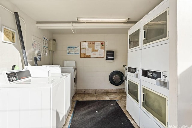 laundry area featuring stacked washing maching and dryer, washer and clothes dryer, and dark tile patterned flooring