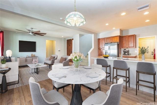 dining space with light hardwood / wood-style floors, ceiling fan, and sink