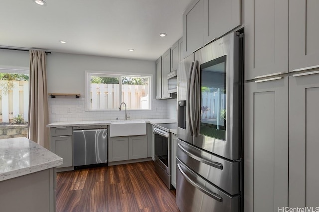 kitchen with gray cabinetry, sink, decorative backsplash, and stainless steel appliances