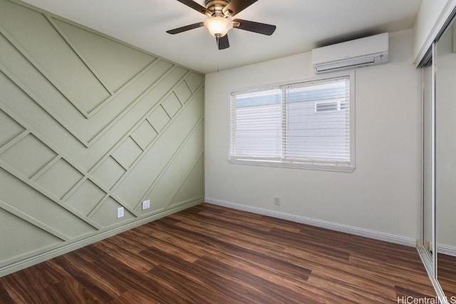 spare room featuring dark wood-type flooring, a wall mounted air conditioner, and ceiling fan