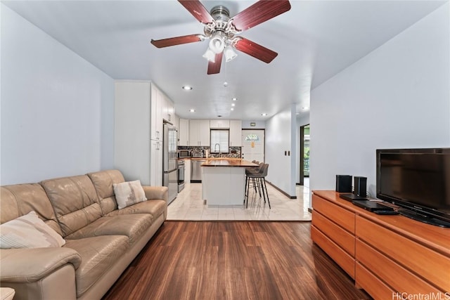 living room with sink, ceiling fan, and light hardwood / wood-style flooring