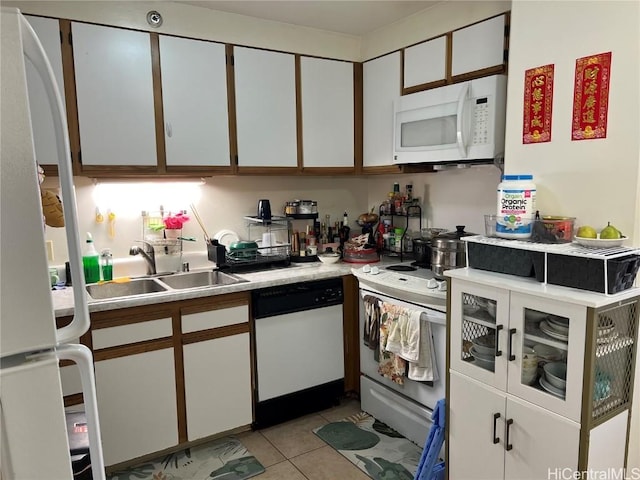 kitchen with sink, light tile patterned floors, white cabinets, and white appliances