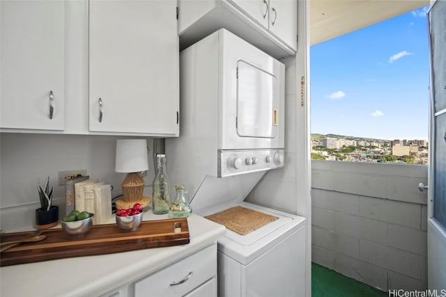 clothes washing area featuring cabinets and stacked washer / dryer