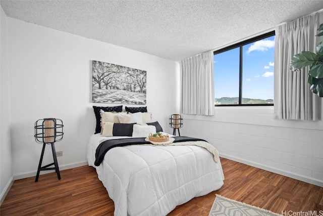 bedroom with dark hardwood / wood-style floors and a textured ceiling