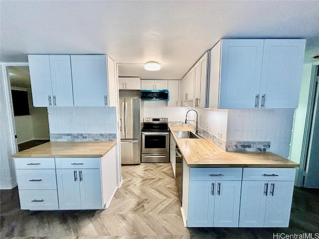 kitchen featuring sink, exhaust hood, white cabinetry, appliances with stainless steel finishes, and backsplash