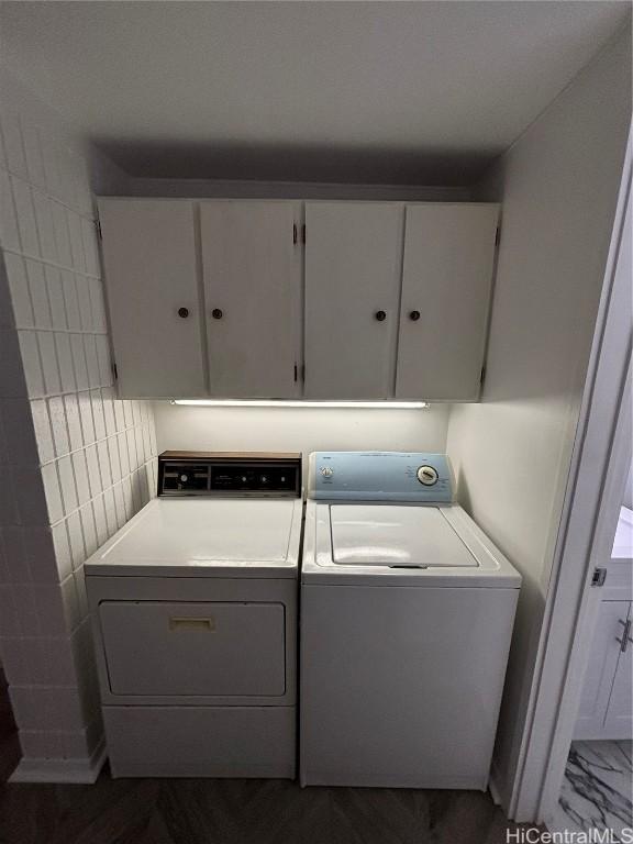 clothes washing area with cabinets and washer and clothes dryer