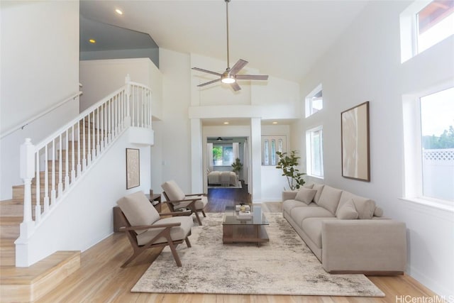 living area featuring a towering ceiling, baseboards, wood finished floors, and stairs