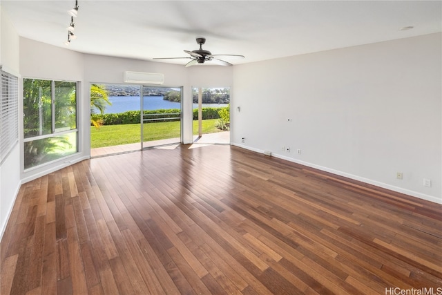 unfurnished room featuring rail lighting, ceiling fan, a water view, dark hardwood / wood-style flooring, and an AC wall unit