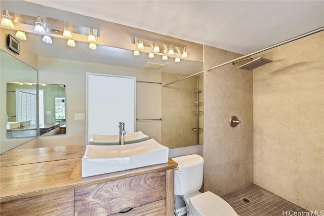 bathroom with vanity, tiled shower, and toilet