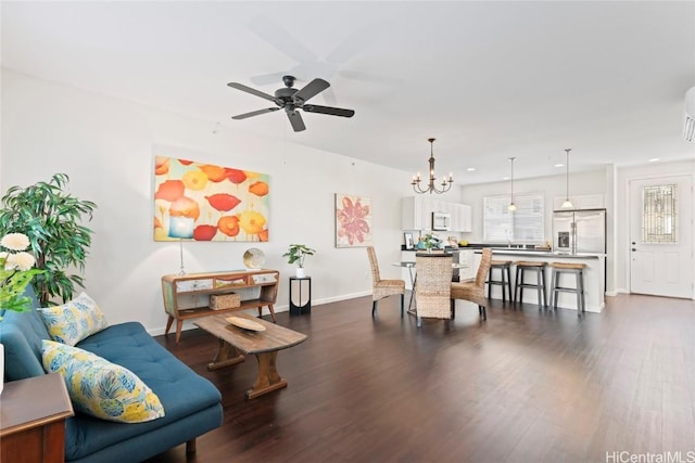 living room featuring recessed lighting, baseboards, dark wood-type flooring, and ceiling fan with notable chandelier