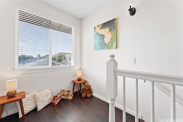 sitting room with wood finished floors, an upstairs landing, and baseboards