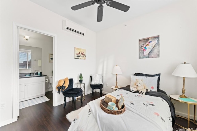 bedroom with baseboards, dark wood finished floors, ensuite bathroom, an AC wall unit, and a sink