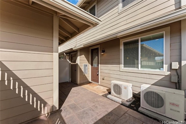 view of exterior entry with ac unit and a patio