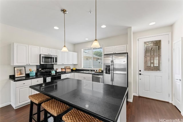 kitchen with dark countertops, dark wood-style floors, stainless steel appliances, white cabinetry, and a sink