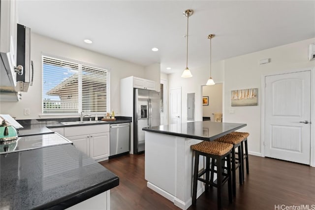 kitchen featuring stainless steel appliances, a sink, white cabinetry, dark wood-style floors, and dark countertops