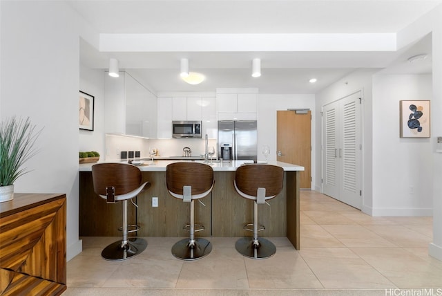 kitchen with white cabinetry, appliances with stainless steel finishes, a kitchen breakfast bar, and kitchen peninsula