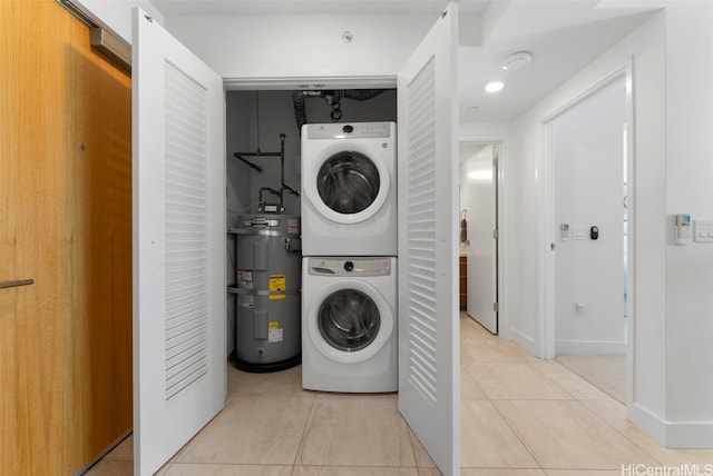 clothes washing area featuring stacked washer and dryer, water heater, and light tile patterned floors