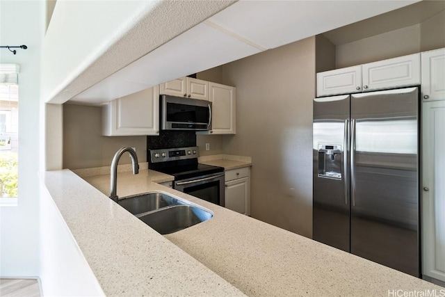 kitchen with light stone countertops, appliances with stainless steel finishes, sink, and white cabinets