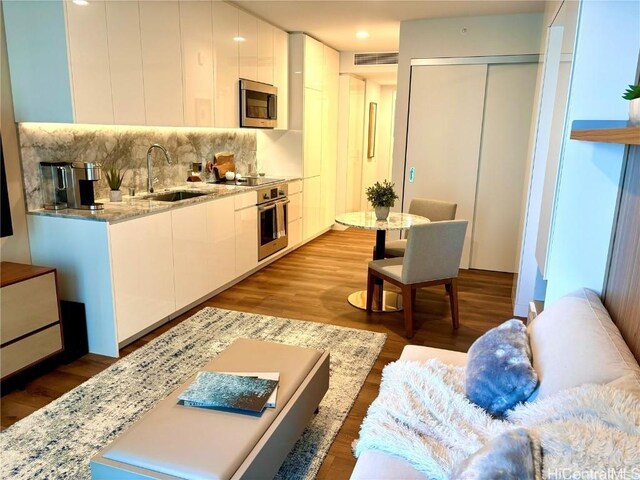 kitchen with sink, backsplash, white cabinets, and appliances with stainless steel finishes