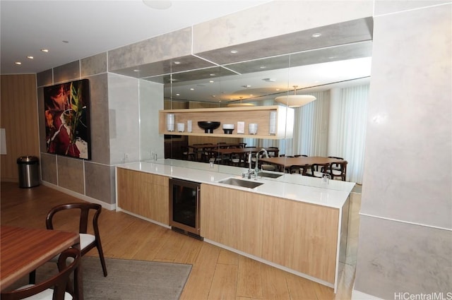 interior space featuring hanging light fixtures, sink, beverage cooler, and light hardwood / wood-style floors