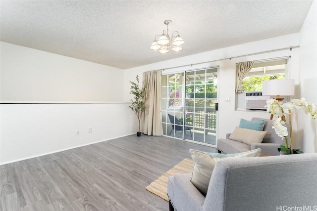 unfurnished room featuring hardwood / wood-style flooring, an inviting chandelier, and a textured ceiling