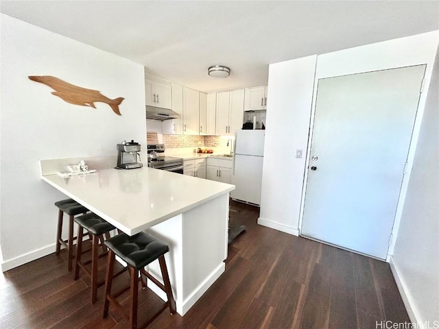 kitchen with white cabinetry, a kitchen breakfast bar, stainless steel range with electric cooktop, kitchen peninsula, and white fridge