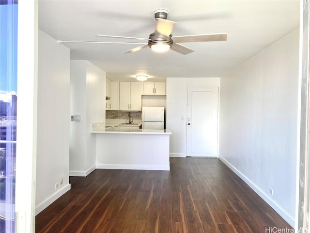 kitchen with sink, white cabinetry, kitchen peninsula, white fridge, and decorative backsplash