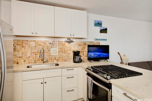 kitchen featuring sink, white cabinetry, tasteful backsplash, stainless steel appliances, and light stone countertops